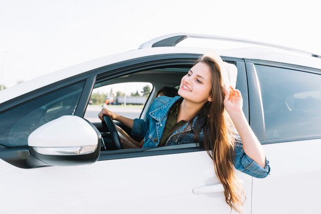 車の窓からぶら下がっている幸せな女性