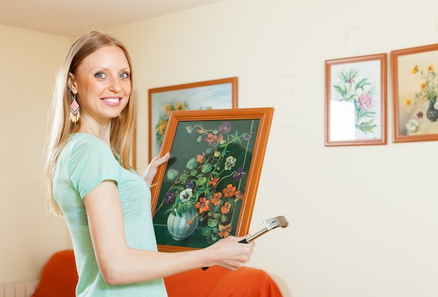 Happy woman hanging the  pictures