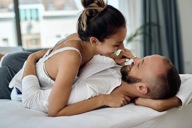 무료 사진 남자친구와 즐거운 시간을 보내고 침대에서 휴식을 취하면서 코를 만지는 행복한 여자