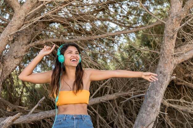 Happy woman in headset listening to music in forest