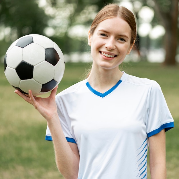 Счастливая женщина, держащая мяч за пределами