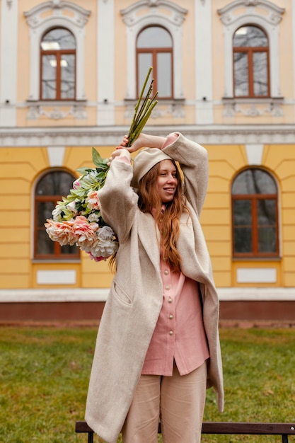 Foto gratuita donna felice che tiene il mazzo di fiori all'aperto in primavera