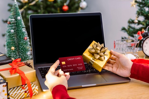 クリスマスにプレゼントオンラインショッピングをしているクレジットカードを保持している幸せな女性