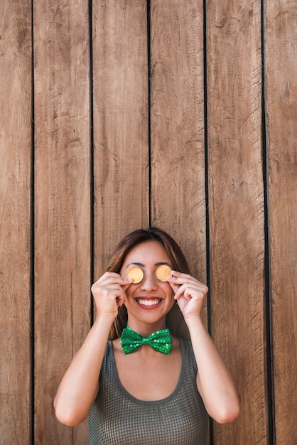 Free photo happy woman holding golden coins near eyes