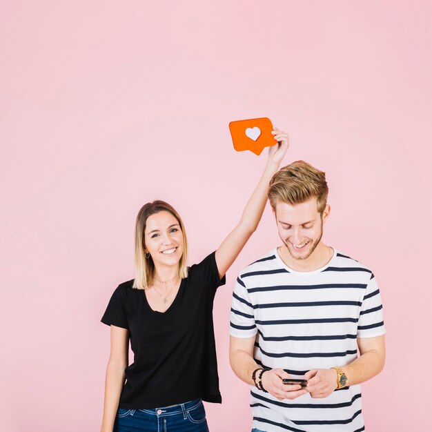 Happy woman holding like icon over man using cellphone