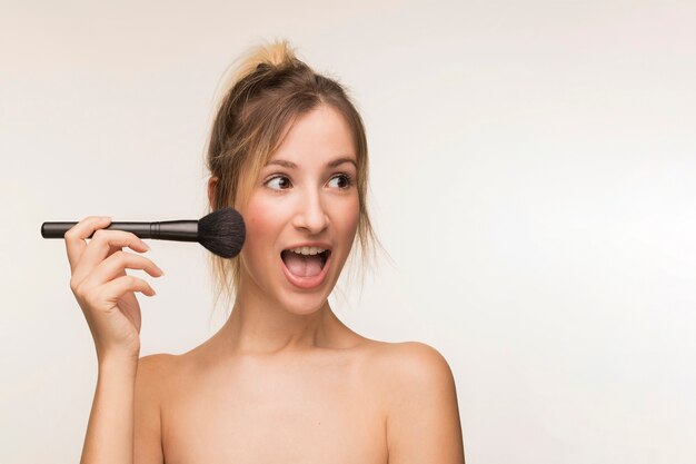 Happy woman holding makeup brush