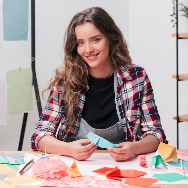 Happy woman holding origami craft looking at camera