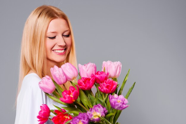 Счастливая женщина, держащая розовые и фиолетовые тюльпаны