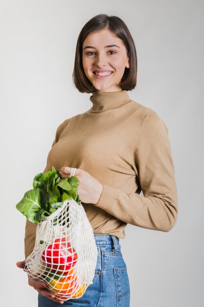 再利用可能な食料品の袋を保持している幸せな女