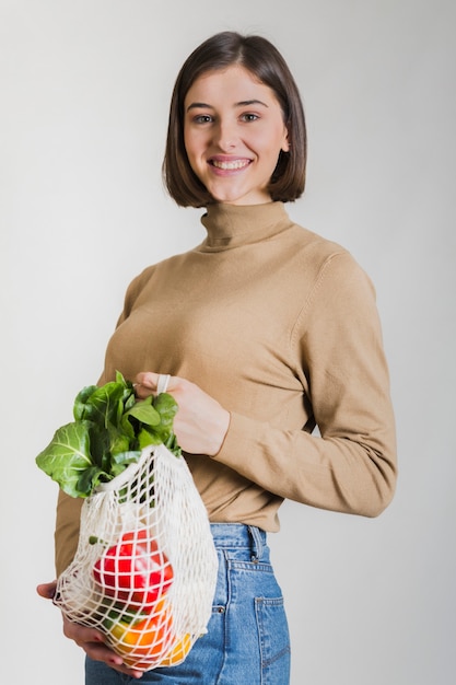 再利用可能な食料品の袋を保持している幸せな女