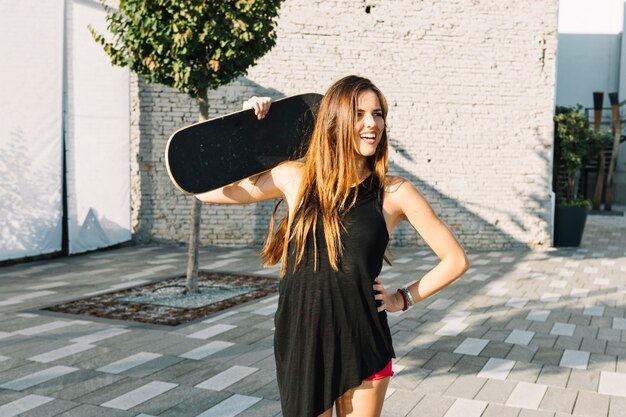 Счастливый женщина, проведение скейтборд на открытом воздухе