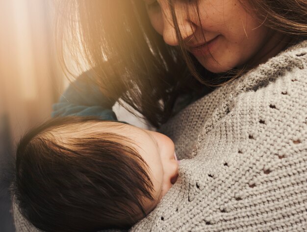 Happy woman holding sleeping baby in arms