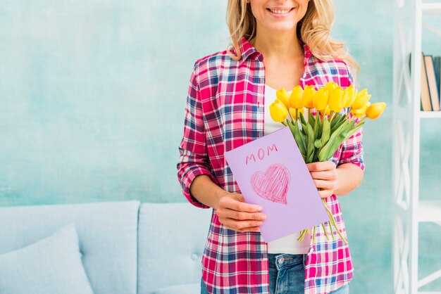 Happy woman holding tulips and greeting card
