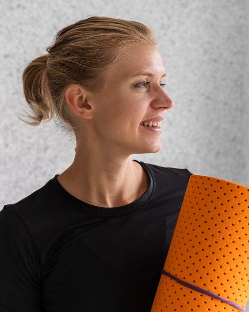 Happy woman holding yoga mat