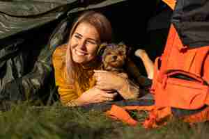 Free photo happy woman hugging her dog and sitting in tent