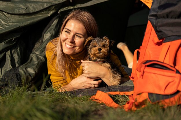 犬を抱きしめてテントに座って幸せな女性