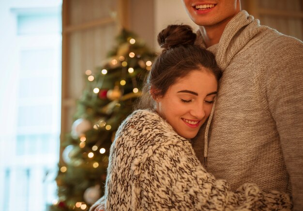 Happy woman hugging man at Christmas tree