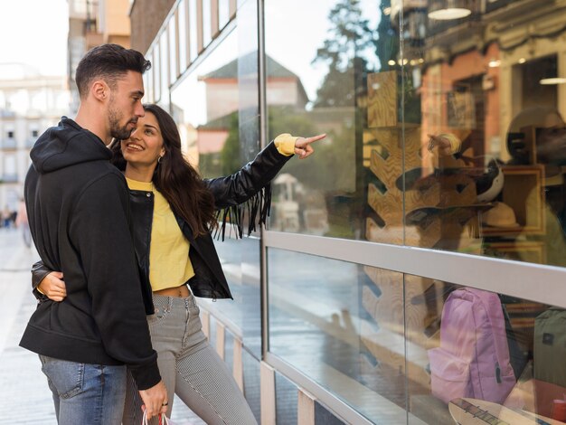 Happy woman hugging and showing on shop window to young man
