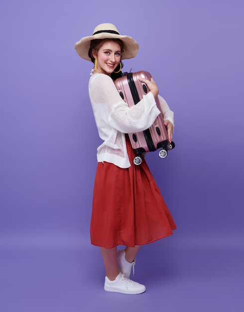 Счастливая женщина обнимает чемодан на фиолетовом фоне