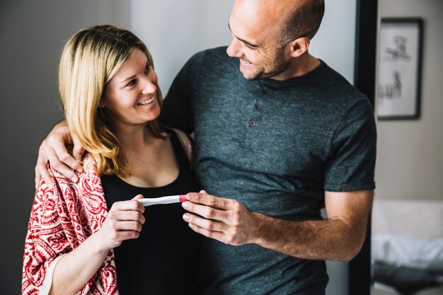 Happy woman and husband looking at pregnancy test