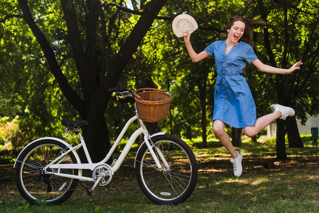 Foto gratuita donna felice che salta accanto alla bici