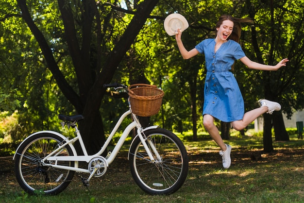 Happy woman jumping next to bike