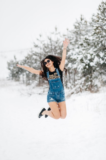 Foto gratuita donna felice che salta nella foresta di inverno