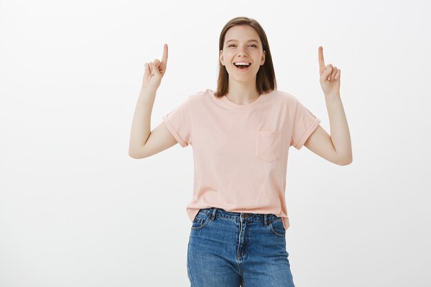 Happy woman laughing and smiling, pointing fingers up at your logo, banner promo