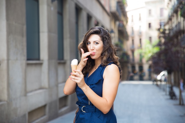 Foto gratuita donna felice leccare il dito mentre mangia il gelato