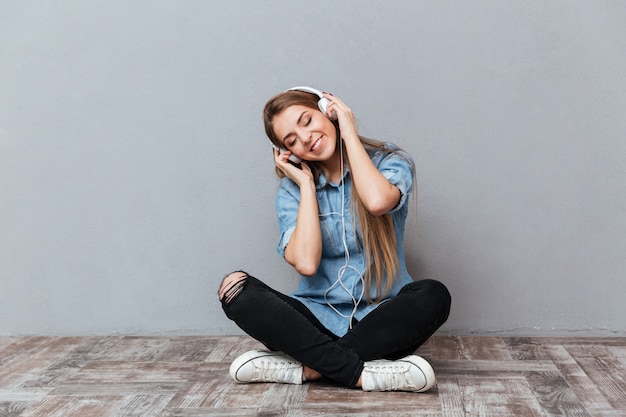 Free photo happy woman listening music on the floor