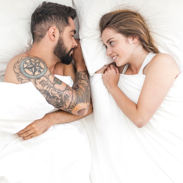 ベッドで眠っている夫を見ている幸せな女性