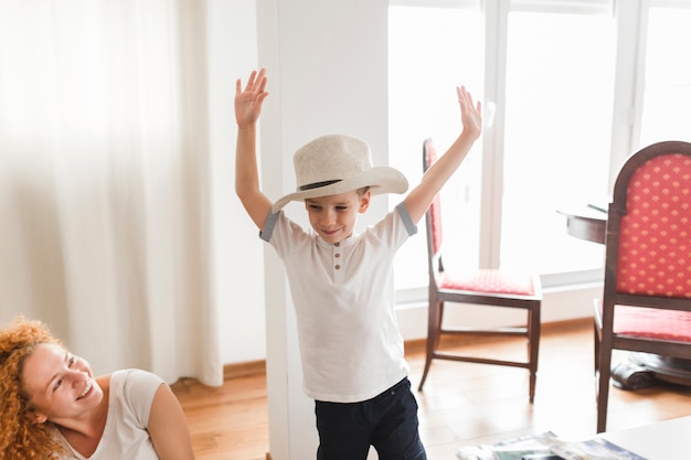 Happy woman looking at playful boy raising his arms