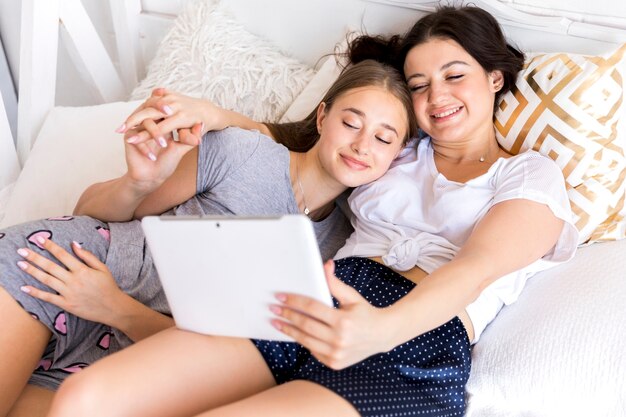 Happy woman looking at tablet with girlfriend
