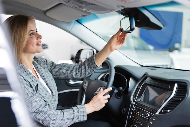 Happy woman looks in the mirror of the car