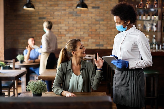 Happy woman making an order while talking to black waitress in a cafe