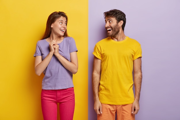 Счастливые женщина и мужчина с радостью смотрят друг на друга, одетые в яркую летнюю одежду, веселятся