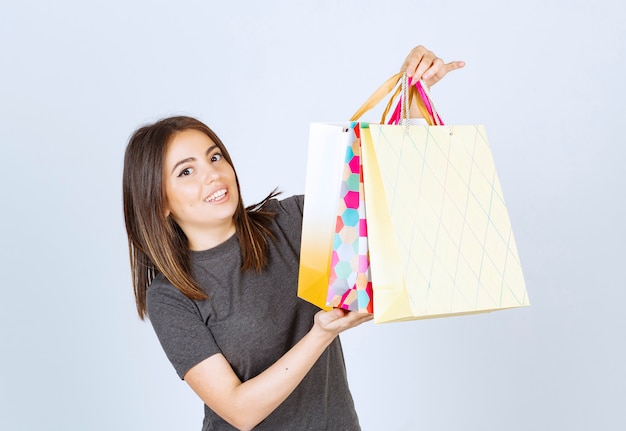 A happy woman model holding a lot of shopping bags on white background.