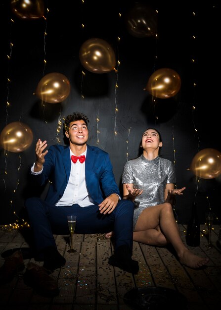 Happy woman near smiling man between tossing balloons 