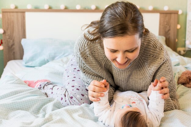 幸せな女の赤ちゃんがベッドの上で遊んで