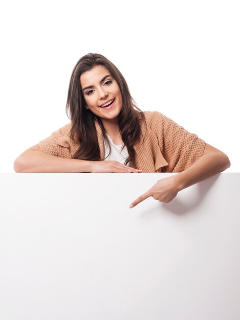 Happy woman pointing at empty whiteboard