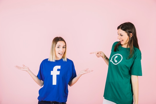 Happy woman pointing at her friend shrugging