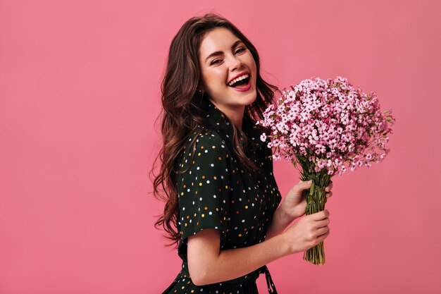 Happy woman in polka dot outfit laughing and holding flowers