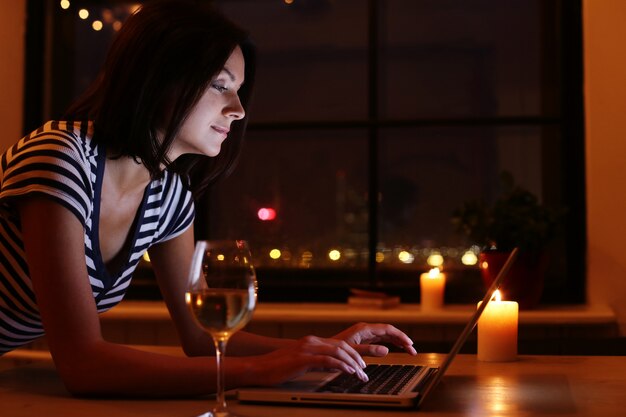 happy woman portrait with glass of wine looking at pc screen