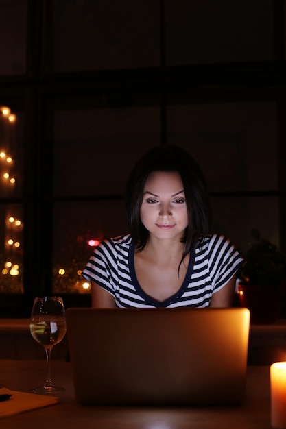 Free photo happy woman portrait with glass of wine looking at pc screen