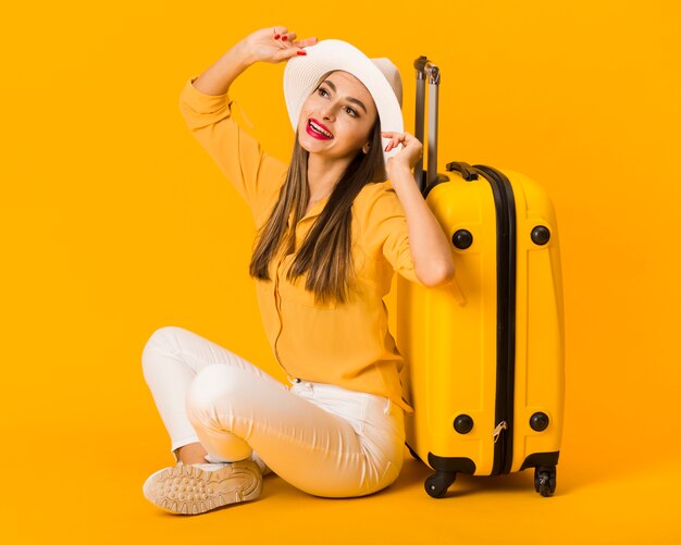 Happy woman posing next to luggage