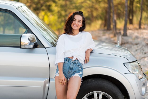 Happy woman posing near car