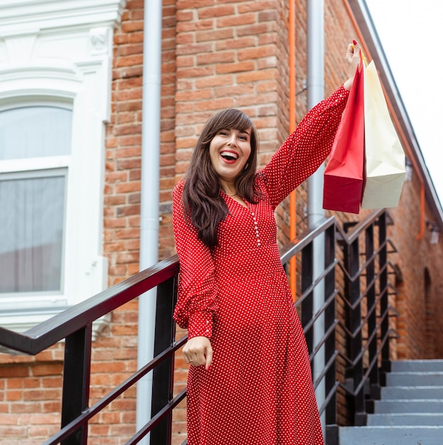 Happy woman posing outdoors with lots of shopping bags