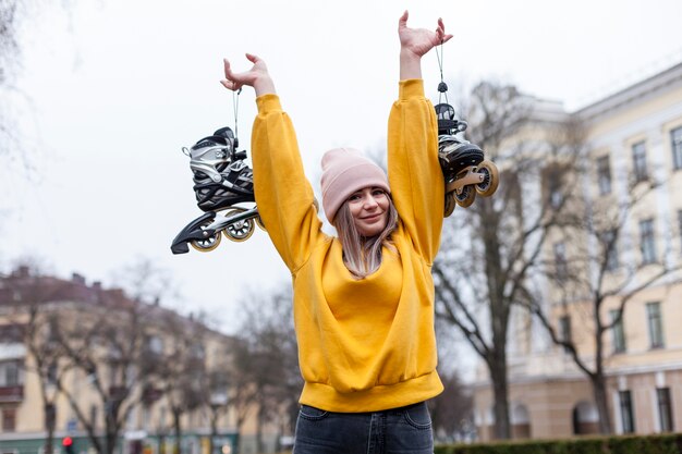 Happy woman posing while holding roller blades