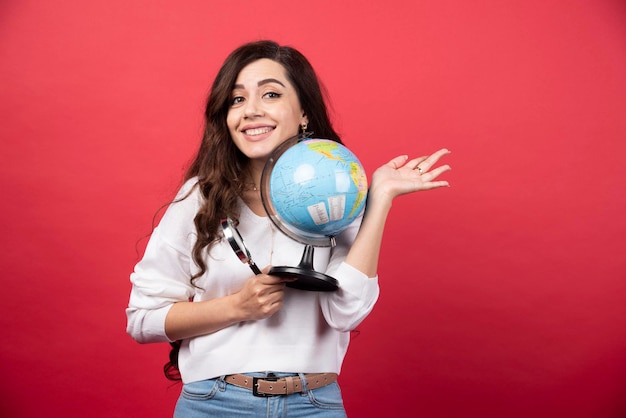 Foto gratuita donna felice che posa con il globo e la lente d'ingrandimento. foto di alta qualità