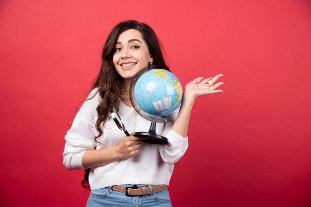 Happy woman posing with globe and magnifying glass. High quality photo